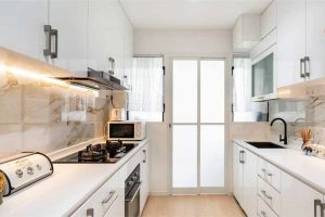 Modern minimalist HDB kitchen interior with white cabinets, marble backsplash, gas hob, and black faucet.